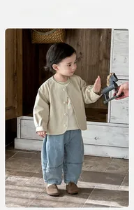 Détail du cardigan beige et du pantalon en jean bleu clair pour petit garçon bébé