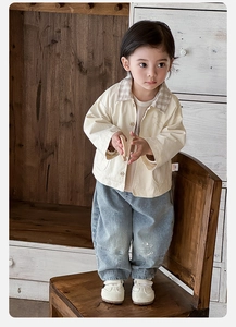Détail de la veste beige pour petit garçon avec col à carreaux et jean bleu clair