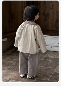 Back view of toddler beige lapel jacket and wide-leg trousers in a vintage setting