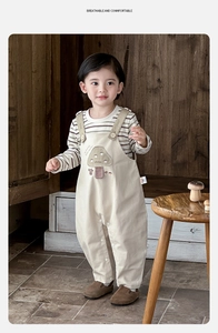 Détail de la tenue pour bébé avec broderie champignon sur la salopette beige en coton