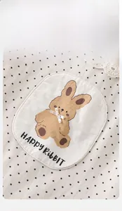 Détail de la tenue bébé avec imprimé à pois, broderie lapin et col en dentelle délicate