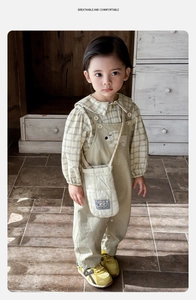 Détail d'une chemise à carreaux pour garçon et d'une salopette kaki avec patch brodé
