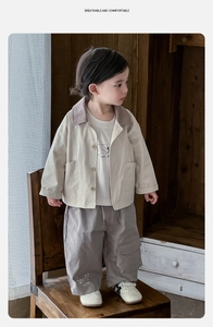 Detailed view of beige jacket, white tee and grey cargo pants on a toddler boy