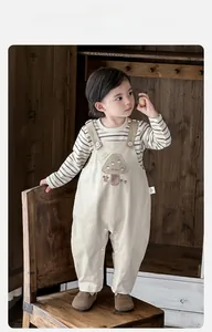 Détail du haut rayé pour bébé garçon et de la salopette beige avec broderie champignon