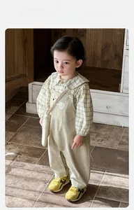 Détail de l'ensemble chemise à carreaux beige et salopette avec écusson chiot brodé