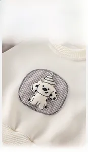Detail of baby sweatshirt featuring cute cartoon dog embroidery and rib knit neckline