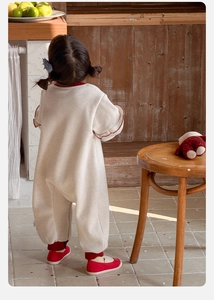 Detail of baby girl bodysuit featuring cream knit fabric and red trim on back