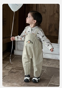 Detail of toddler boy set showing cartoon car print shirt and beige suspender pants