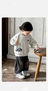 Close-up of boys' grey cartoon sweatshirt and denim pants set with car applique detail
