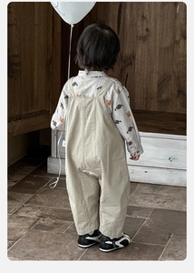 Detail of baby boy cartoon print shirt and beige suspender pants set for spring