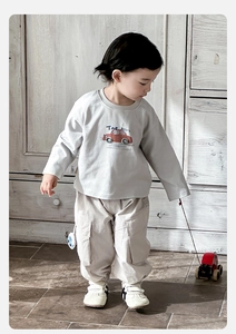 Detail of toddler boy set with grey car print t-shirt and beige cargo pants in home setting
