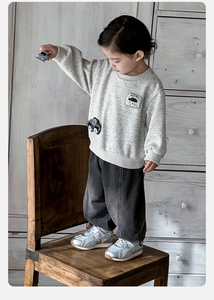 Detail of grey cartoon sweatshirt with Rain Day embroidery and dark wash denim pants