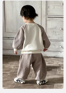 Rear view of toddler boy in color-block sweatshirt and joggers set at home