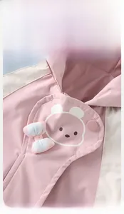 Close-up of pink hooded jacket detail with bear patch and plaid bow decoration