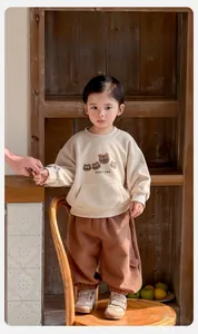 Detail of cartoon bear print and front pocket on beige toddler sweatshirt set