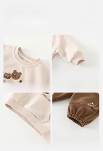 Detailed views of ribbed cuffs, bear print, and cotton fabric on a toddler tracksuit