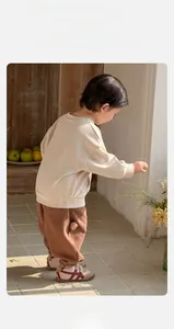 Detail of baby boy's beige sweatshirt and brown knit pants with cozy texture and side accents