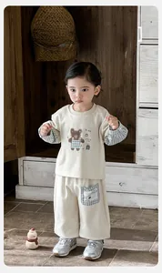 Detail of baby tracksuit with bear print and blue checkered pockets in indoor scene