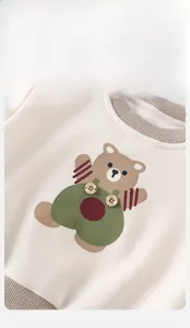 Detailansicht des Bären-Aufdrucks und des Rippbündchens am beigen Baby-Sweatshirt
