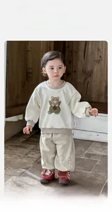 Detailaufnahme eines cremefarbenen Baby-Sweatshirts mit Bärenprint und braunen Rippbündchen