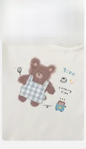 Close-up of beige cotton toddler sweatshirt featuring a cute brown bear with cooking prints