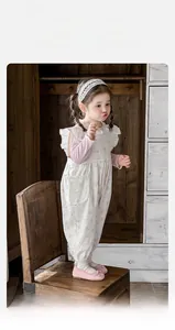 Detail of girls floral jumpsuit with ruffled shoulders and pink long sleeve inner layer