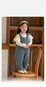 Detailed view of baby girl's blue polka dot overalls with a lace-trimmed beige long sleeve shirt