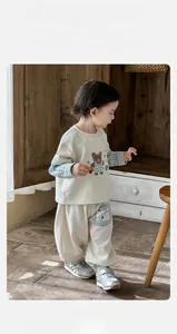 Detail of baby beige sweatshirt set with bear print and blue checkered patchwork sleeves