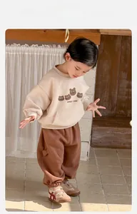 Detail of baby boy beige bear sweatshirt and brown pants set with pocket design