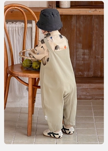 Close-up of beige cartoon shirt and green suspender pants for toddlers in a vintage room