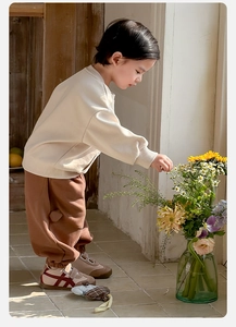 Detail of baby boy cartoon outfit with beige sweatshirt and brown pants with heart pocket