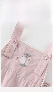 Detailed embroidery of a rabbit and floral patterns on a pink baby girl overall dress