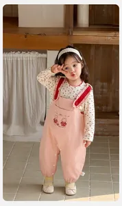Détail de la salopette rose pour bébé avec broderie lapin et chemise à fleurs