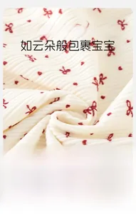 Gros plan sur tissu côtelé crème doux avec motifs de nœuds rouges pour bébés