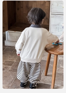 Dettaglio della felpa beige per bambini e pantaloni a righe visti dal retro