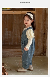 Detail of baby girl spring set with blue bow-print overalls and yellow puff sleeve shirt