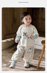 Detail of baby cotton tracksuit with cute bear print and blue checkered sleeve patches