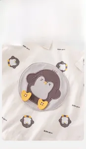Close-up of baby bib with large penguin appliqué and yellow heart-shaped button details