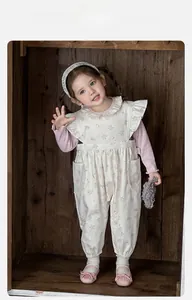 Close-up of pink long-sleeve top with ruffle collar and floral print overalls