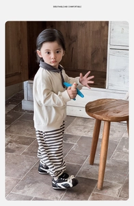 Dettaglio felpa polo beige per bambini e pantaloni a righe in cotone di alta qualità
