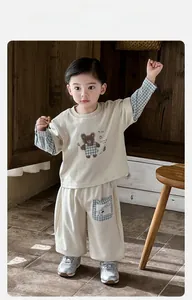 Detail of baby cotton tracksuit set with bear print and plaid sleeves on wooden background