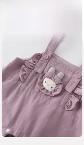 Détail de la salopette bébé en coton violet avec volants et écusson lapin