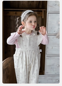 Detail of baby girl floral overalls with pink ribbed long sleeve top and ruffle neckline