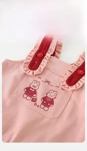 Détail d'une salopette rose pour bébé avec broderie lapin et bretelles à volants rouges