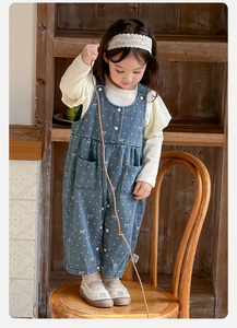 Detail of baby girl outfit with dot pattern denim overalls and ribbed long sleeve shirt