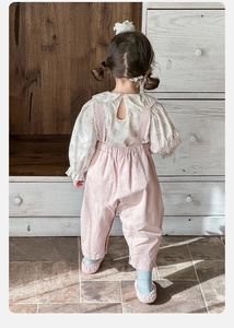 Detail view of floral shirt ruffle collar and pink overall trousers for toddler girls