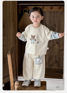 Detail of baby beige sweatshirt set with checkered sleeves and cartoon bear print