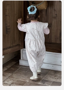 Detail of baby girl floral romper with ruffles and back button closure on cotton fabric