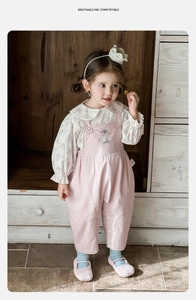 Detail of floral long-sleeve shirt with ruffled collar and pink embroidered overalls