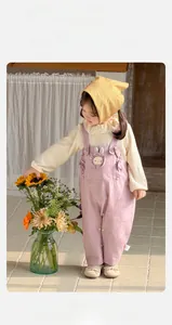 Détail tenue bébé fille avec chapeau à fleurs, haut crème et salopette lapin mauve